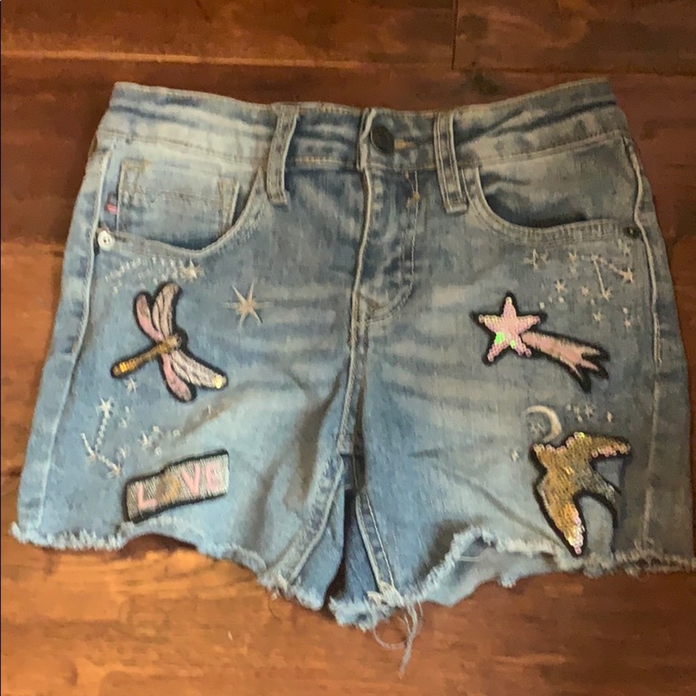 They are a pair of blue denim shorts with patches